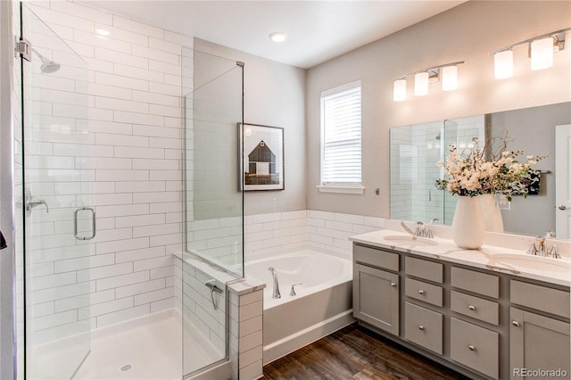 bathroom featuring a shower stall, a sink, a garden tub, and wood finished floors
