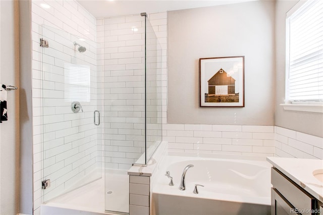 bathroom featuring a shower stall, a garden tub, and vanity