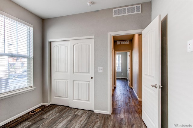 unfurnished bedroom featuring baseboards, visible vents, dark wood-style floors, and a closet