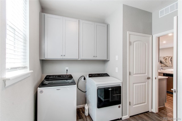 washroom featuring visible vents, cabinet space, dark wood finished floors, and washing machine and clothes dryer