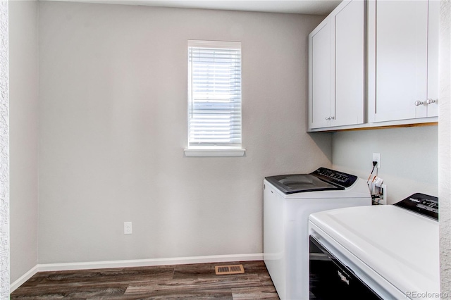 laundry room featuring baseboards, cabinet space, washing machine and dryer, and dark wood-style floors