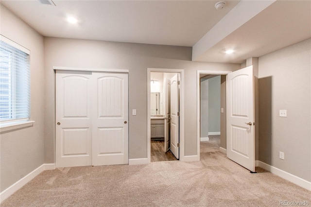 unfurnished bedroom with carpet floors, baseboards, ensuite bath, and a closet