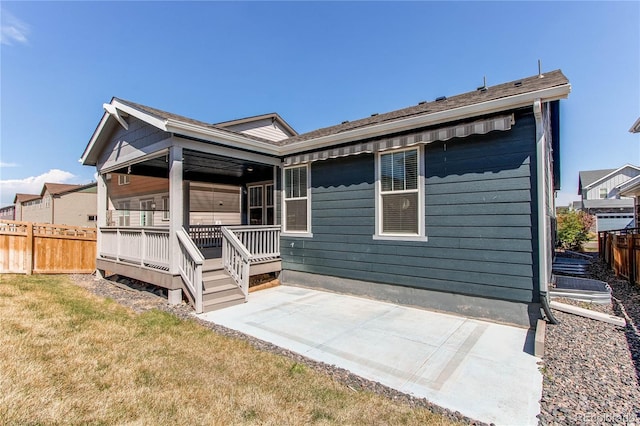 rear view of property featuring a lawn, a patio, and fence