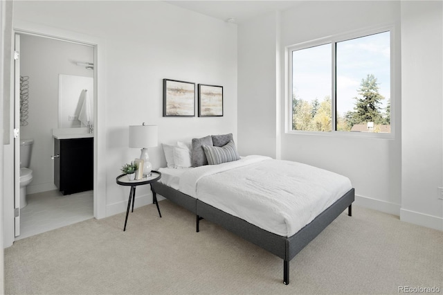 bedroom featuring light colored carpet and ensuite bathroom