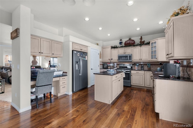 kitchen featuring stainless steel appliances, dark hardwood / wood-style floors, a center island, tasteful backsplash, and cream cabinetry