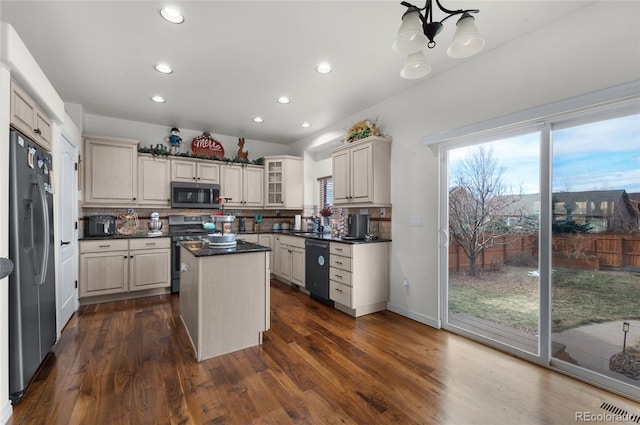 kitchen with sink, dark wood-type flooring, appliances with stainless steel finishes, a kitchen island, and decorative backsplash