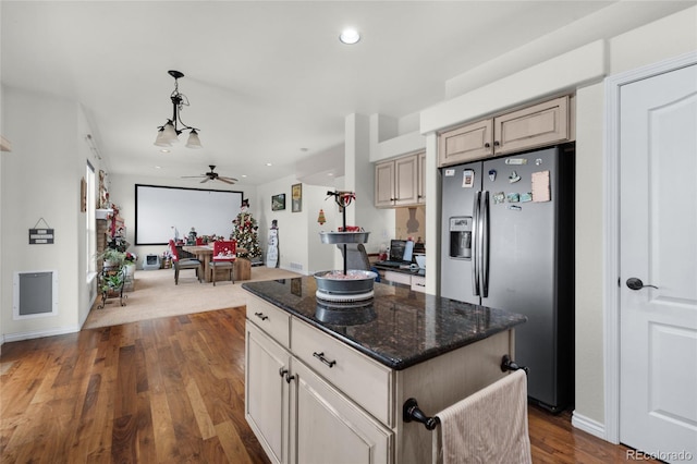 kitchen featuring dark hardwood / wood-style floors, stainless steel fridge, a kitchen island, pendant lighting, and dark stone counters