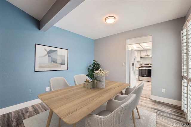 dining space featuring beam ceiling, baseboards, and wood finished floors