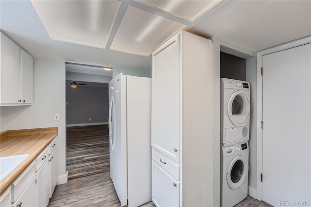 laundry room with ceiling fan, light wood-style flooring, laundry area, stacked washer / dryer, and baseboards