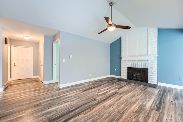 unfurnished living room featuring vaulted ceiling, a fireplace, baseboards, and wood finished floors