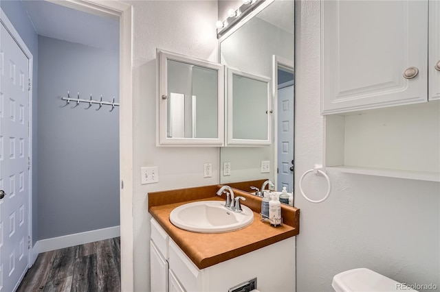 bathroom featuring baseboards, wood finished floors, and vanity