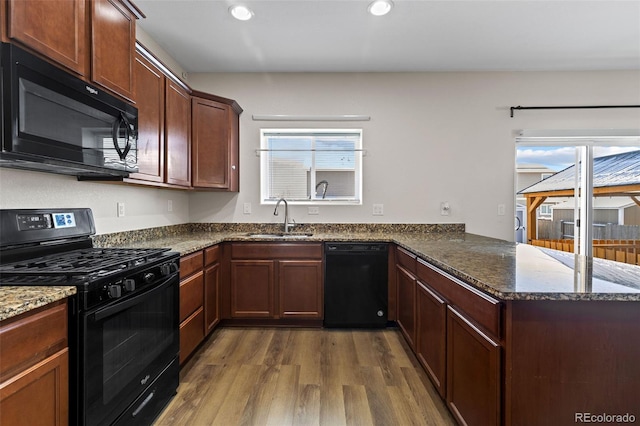 kitchen featuring sink, black appliances, kitchen peninsula, and dark stone counters