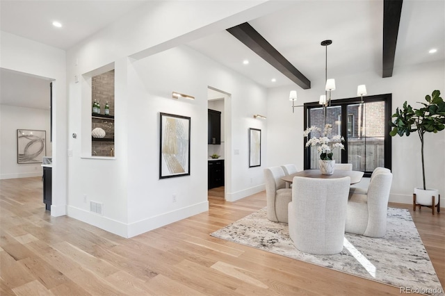 dining area featuring beam ceiling and light wood-type flooring