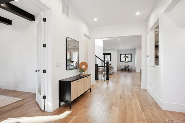 corridor featuring beam ceiling and light hardwood / wood-style flooring