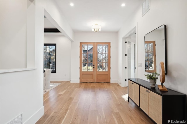 foyer entrance with french doors and light hardwood / wood-style floors