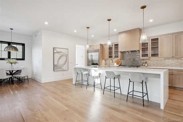 kitchen featuring premium range hood, light brown cabinetry, a spacious island, and stainless steel built in refrigerator