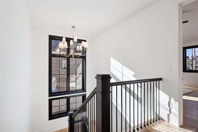 staircase with hardwood / wood-style floors and an inviting chandelier