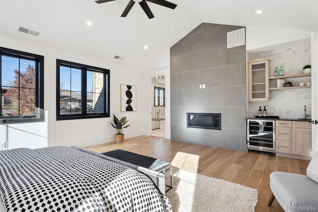 bedroom with vaulted ceiling, light hardwood / wood-style flooring, ceiling fan, indoor wet bar, and beverage cooler