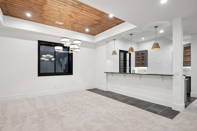 kitchen featuring dark carpet, a raised ceiling, decorative light fixtures, wood ceiling, and a breakfast bar area