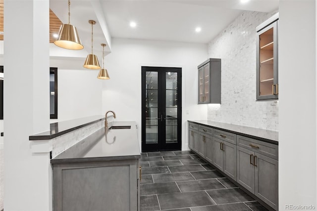 kitchen featuring gray cabinetry, french doors, sink, decorative light fixtures, and kitchen peninsula