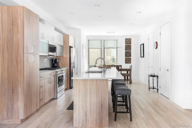 879 Delaware St, Denver, CO 80204 - kitchen with stainless steel appliances, modern cabinets, a breakfast bar area, a kitchen island with sink, and recessed lighting