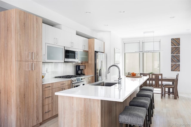 879 Delaware St, Denver, CO 80204 - kitchen with stainless steel appliances, modern cabinets, a kitchen bar, a kitchen island with sink, and tasteful backsplash