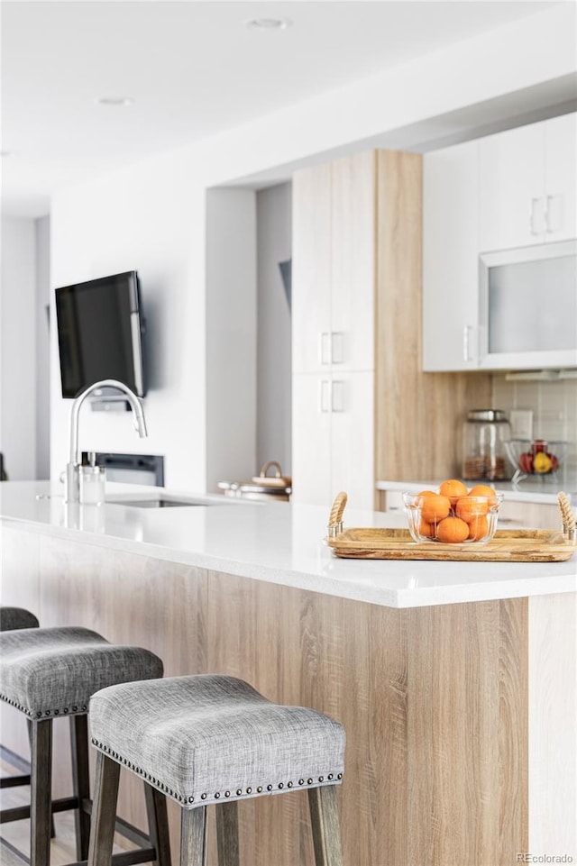 879 Delaware St, Denver, CO 80204 - kitchen featuring a kitchen bar, light countertops, modern cabinets, and white cabinetry