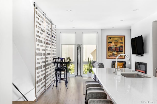879 Delaware St, Denver, CO 80204 - kitchen featuring hardwood / wood-style flooring, a glass covered fireplace, recessed lighting, and a kitchen bar