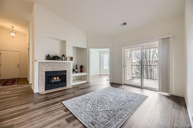 living area with visible vents, a fireplace, baseboards, and wood finished floors