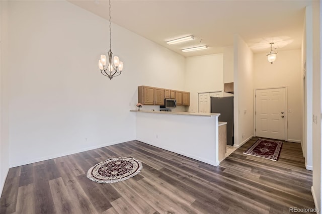 kitchen featuring dark wood finished floors, a towering ceiling, a peninsula, stainless steel appliances, and light countertops