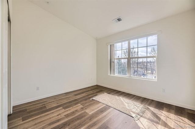 empty room with lofted ceiling, baseboards, visible vents, and wood finished floors