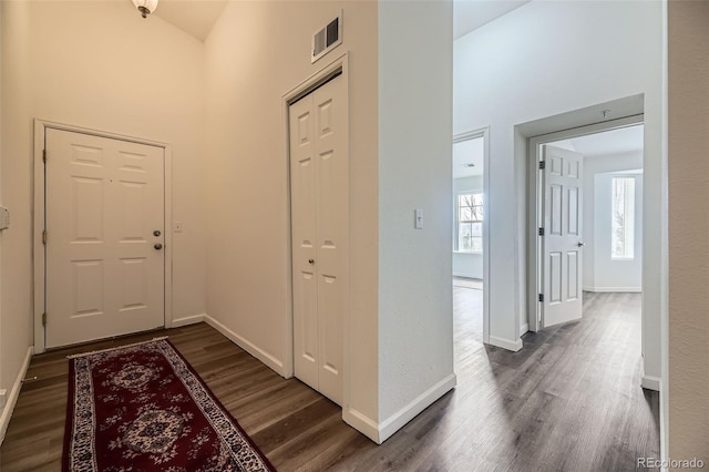 foyer featuring a towering ceiling, wood finished floors, and visible vents