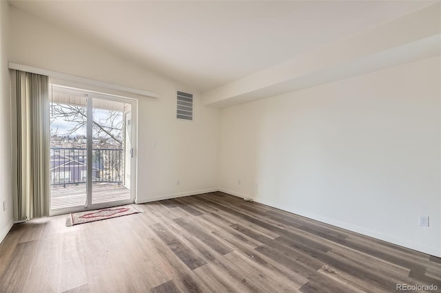 empty room with lofted ceiling, wood finished floors, visible vents, and baseboards