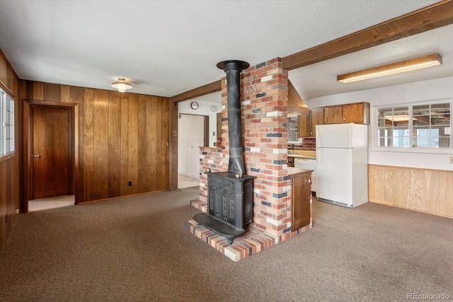 8005 W US Highway 50, Salida, CO 81201 - unfurnished living room featuring wooden walls, a wood stove, carpet, a textured ceiling, and beamed ceiling