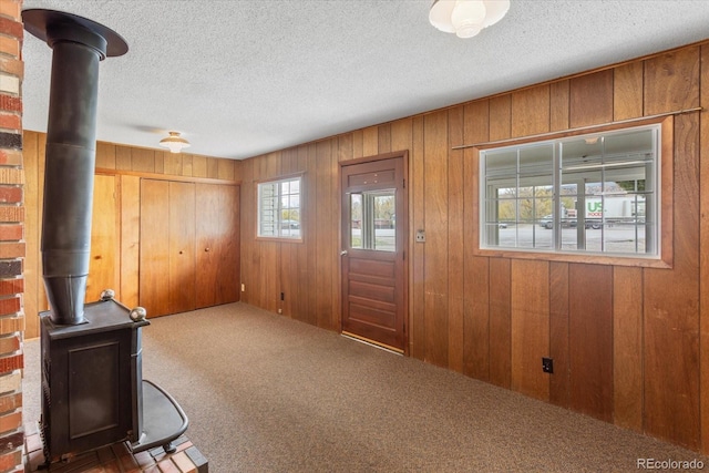 8005 W US Highway 50, Salida, CO 81201 - entrance foyer with carpet floors, a wood stove, wood walls, and a textured ceiling