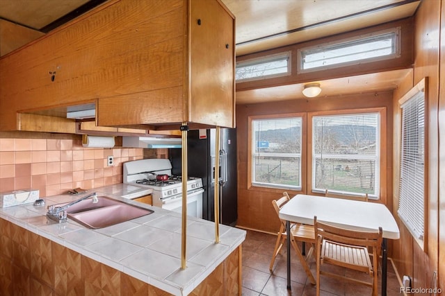 8005 W US Highway 50, Salida, CO 81201 - kitchen featuring tile countertops, white range with gas stovetop, a sink, black refrigerator with ice dispenser, and tasteful backsplash