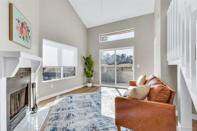 living room featuring a wealth of natural light, baseboards, a fireplace, and high vaulted ceiling