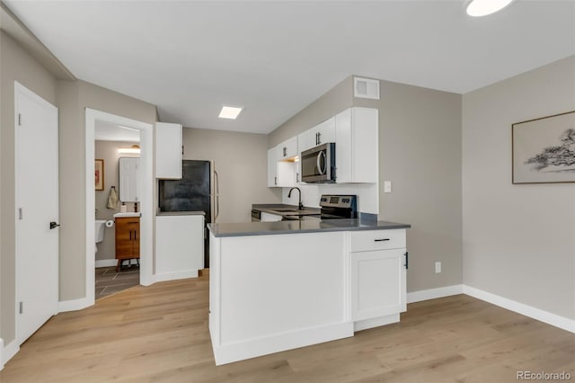 kitchen with white cabinets, stainless steel appliances, visible vents, light wood-type flooring, and baseboards