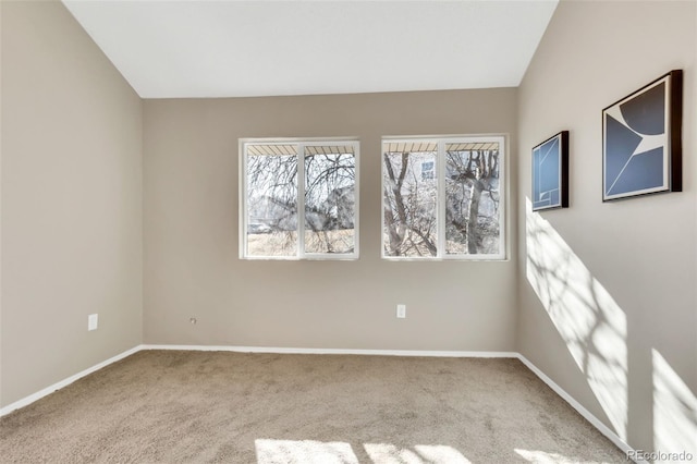 spare room featuring lofted ceiling, baseboards, and carpet flooring