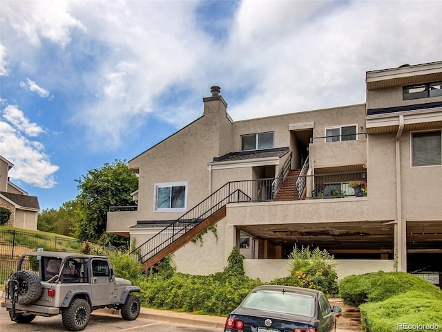 back of house featuring fence, stairs, and stucco siding