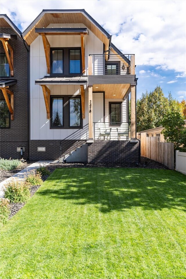 exterior space with a balcony, a porch, and a lawn