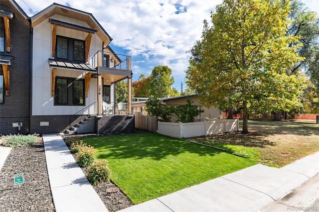 view of front of house featuring a balcony and a front lawn