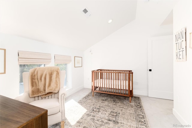 bedroom with light colored carpet, lofted ceiling, and a crib