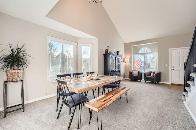 carpeted dining area with high vaulted ceiling