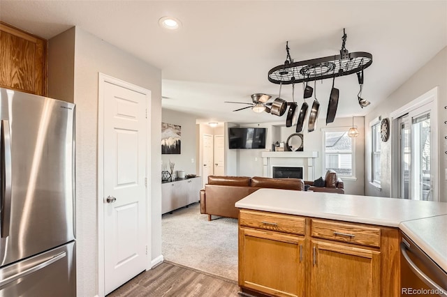 kitchen with ceiling fan, light hardwood / wood-style floors, kitchen peninsula, and stainless steel refrigerator