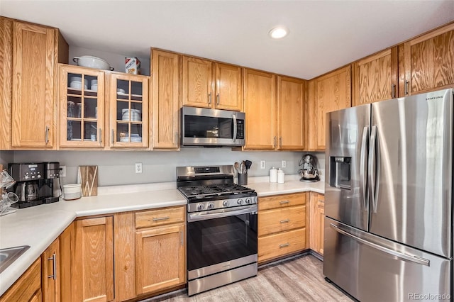 kitchen with stainless steel appliances, light hardwood / wood-style floors, and sink