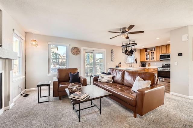 living room featuring light carpet, sink, ceiling fan, and a textured ceiling