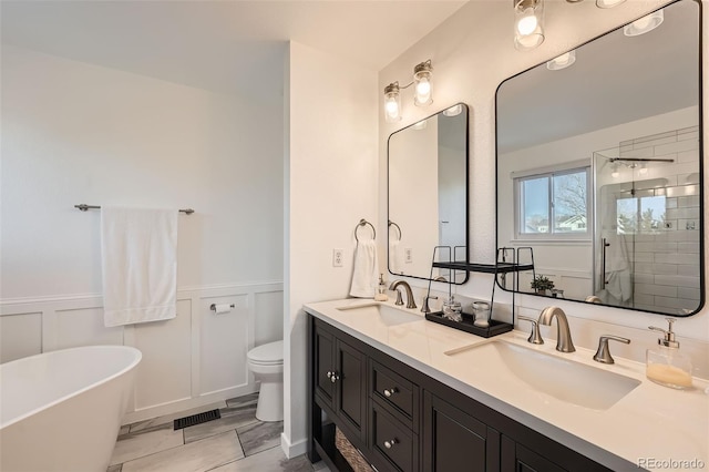 bathroom featuring vanity, a bath, and toilet