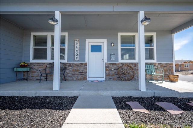 entrance to property with a porch and stone siding