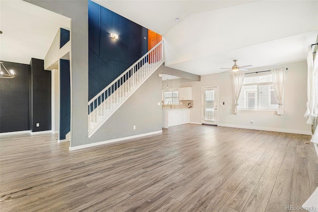 unfurnished living room featuring ceiling fan, wood-type flooring, high vaulted ceiling, and sink